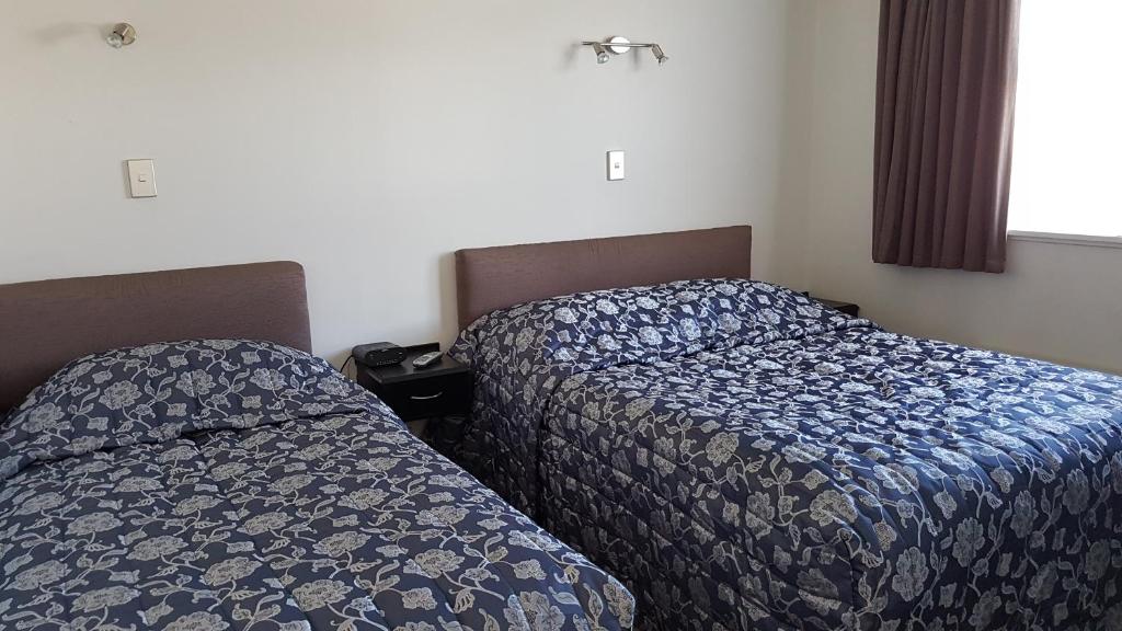 two beds sitting next to each other in a bedroom at Coachman Motel in Taihape