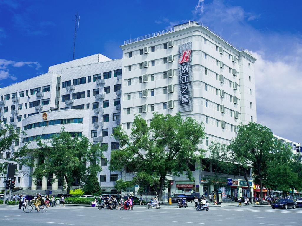 un grande edificio bianco con persone che cavalcano motociclette davanti di Jingjiang Inn Taiyuan Fuxi Street Wanda Plaza a Taiyuan