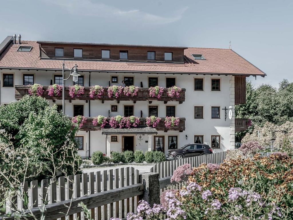 una casa blanca con una valla y flores en Schneiderwirt, en Nussdorf am Inn