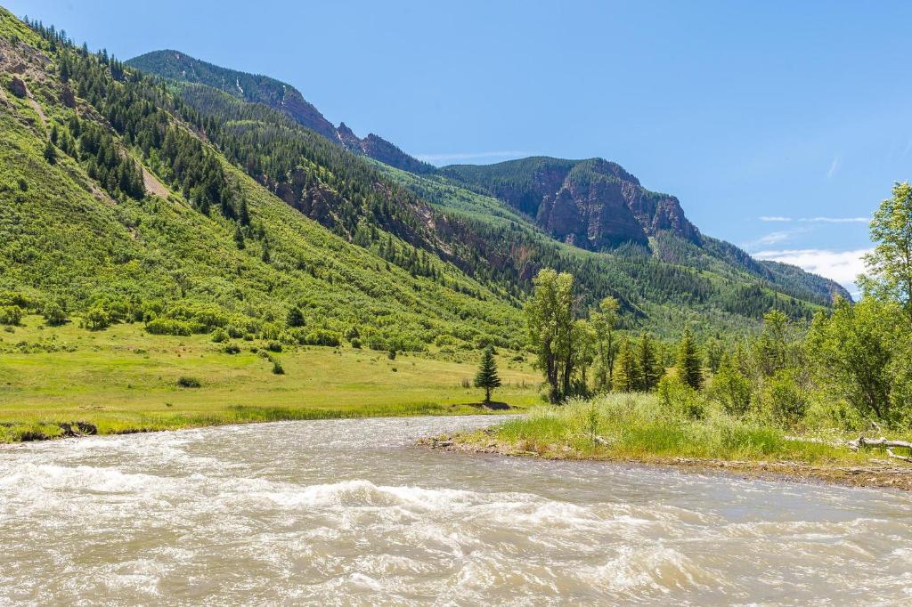 a river in a field with mountains in the background at Three Sisters Peak Cabin at Filoha Meadows in Redstone