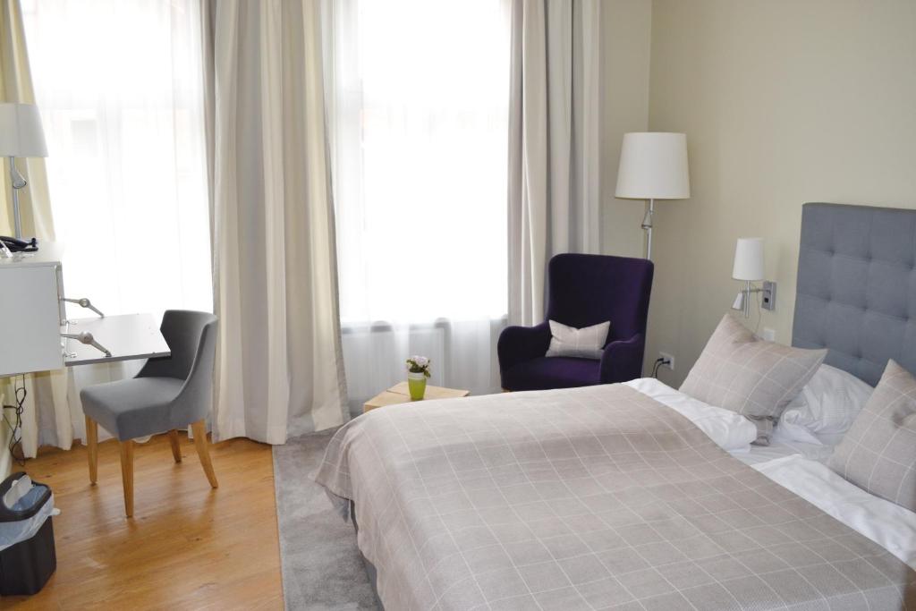 1 Schlafzimmer mit einem Bett, 2 Stühlen und einem Schreibtisch in der Unterkunft Hotel Zum Roten Tore in Lüneburg