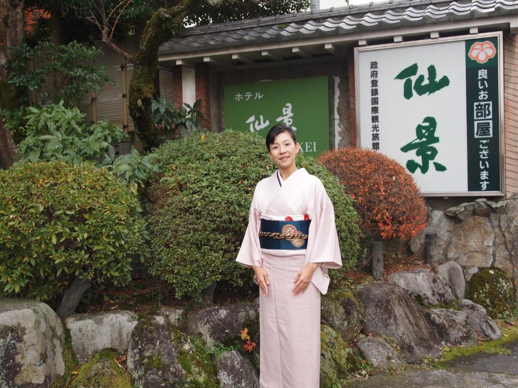a woman in a kimono standing in front of a building at Senkei in Hakone