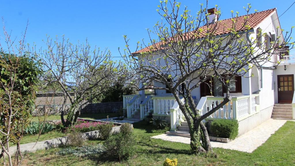 a white house with a tree in the yard at Apartman Matko in Gabonjin
