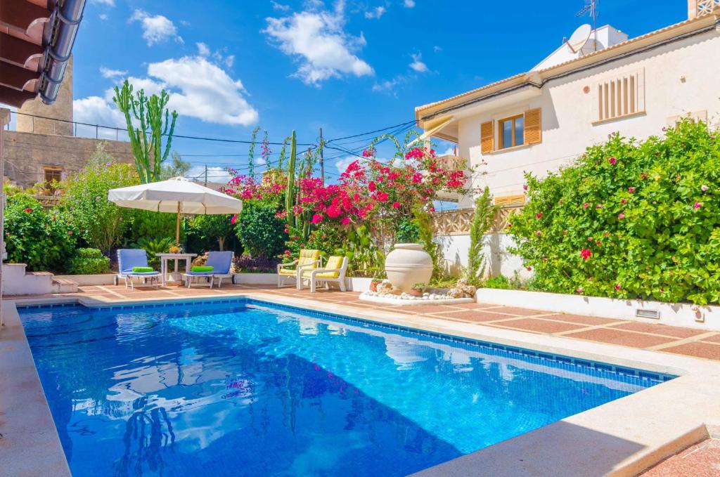 a swimming pool in front of a house with flowers at Can Nicolau in Colonia de Sant Pere