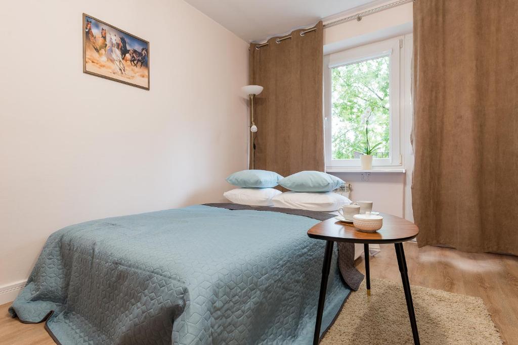 ワルシャワにあるP&O Apartments Kasprzakaのベッドルーム1室(青い枕とテーブル付)