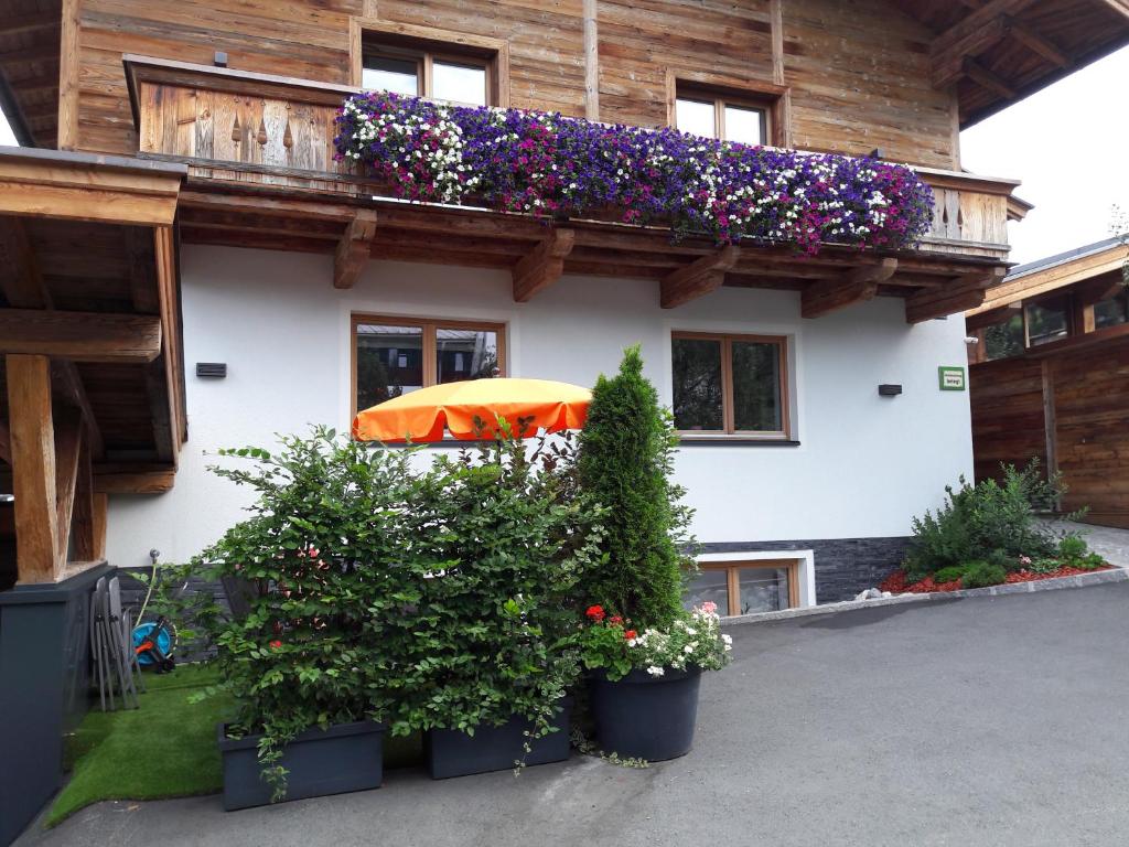 a building with a balcony with flowers and an umbrella at Ferienwohnung Fichtler in Sankt Johann in Tirol