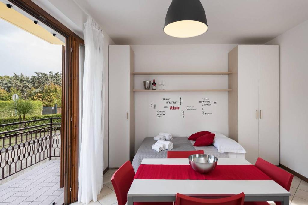 ペスキエーラ・デル・ガルダにあるSan Benedetto di Lugana 3のベッドルーム(ベッド1台、赤い椅子付)、バルコニーが備わります。
