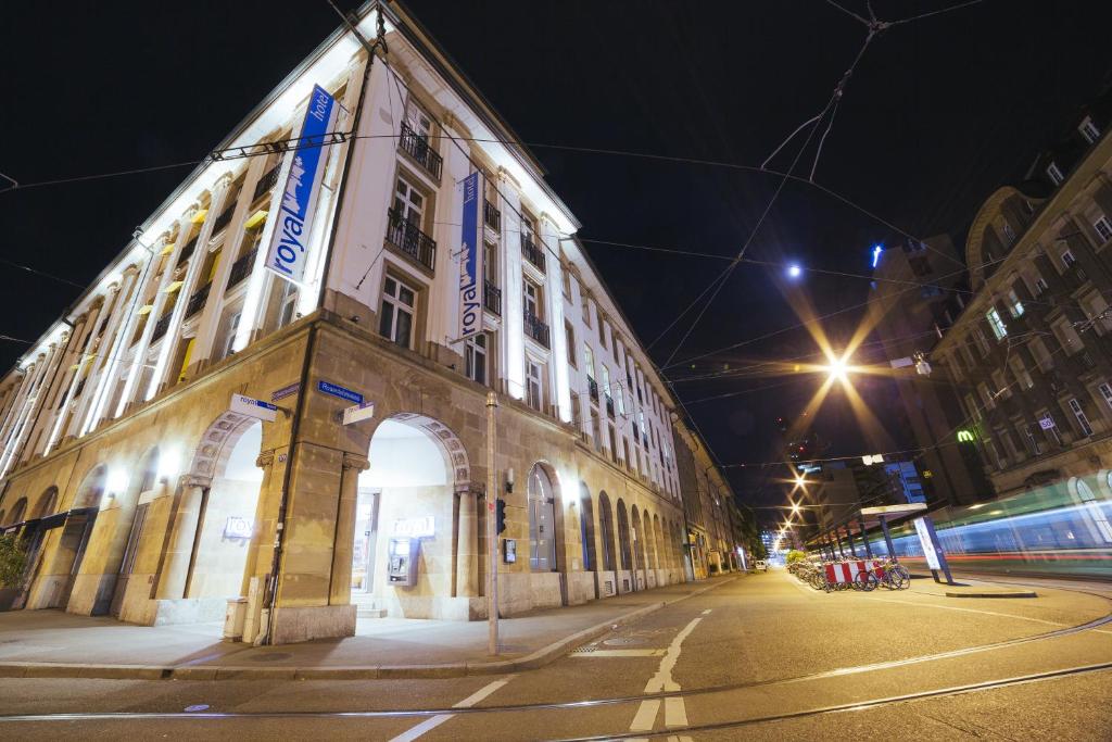 un grand bâtiment dans une rue la nuit dans l'établissement Royal Hotel - Urban Living, à Bâle