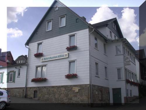 Un bâtiment blanc avec des fleurs sur son côté dans l'établissement Hotel Kilian, à Braunlage