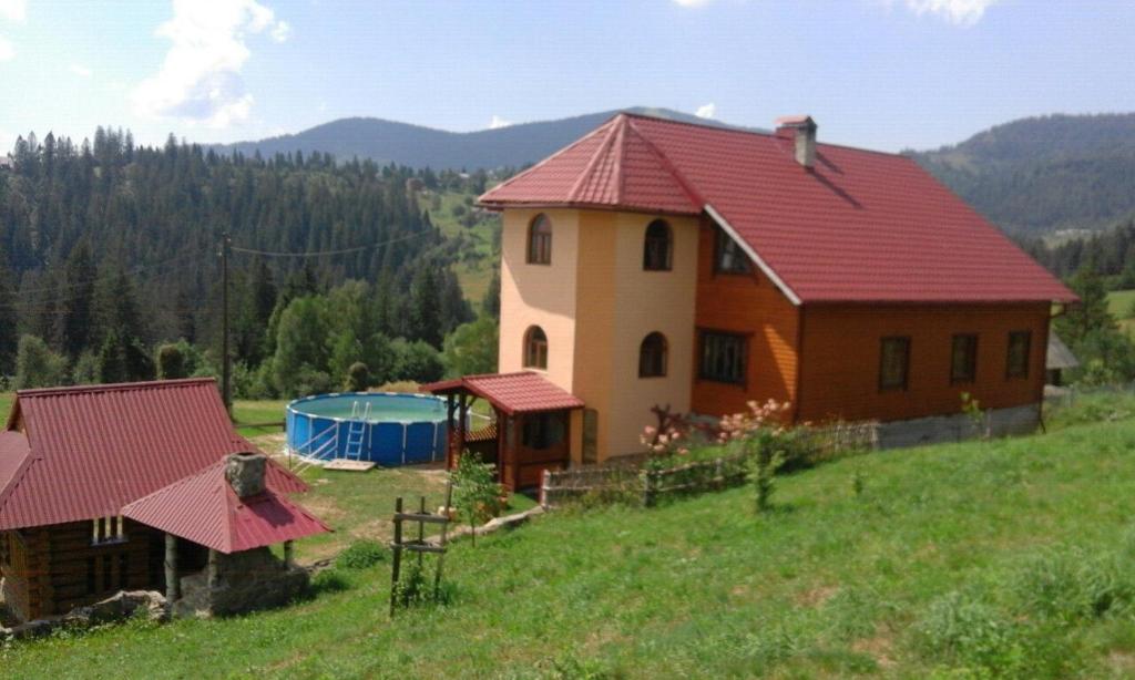 una casa con techo rojo en un campo en Zacharovany Karpaty, en Slavske