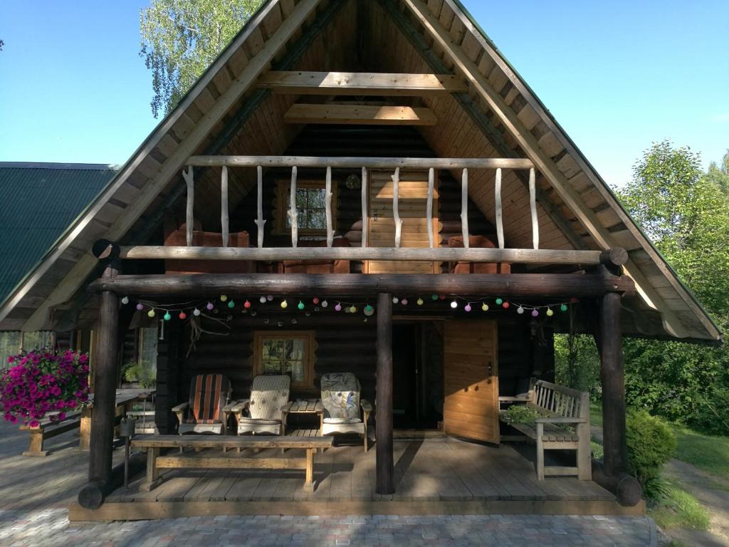 a large wooden cabin with a roof with a porch at Guest House Vējaines in Vecslavēkas