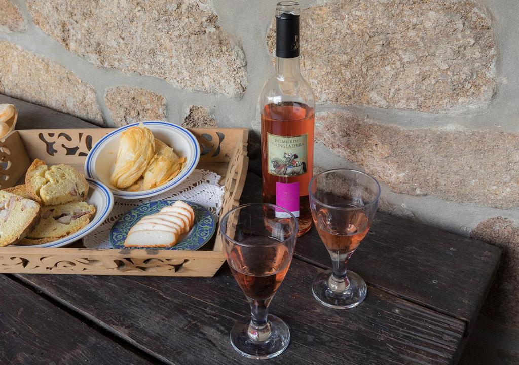Una botella de vino y dos copas en una mesa de madera. en Casas de Selhariz, en Vidago