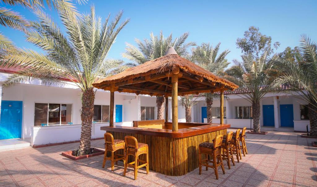a bar in a resort with chairs and palm trees at Fujairah Hotel & Resort in Fujairah