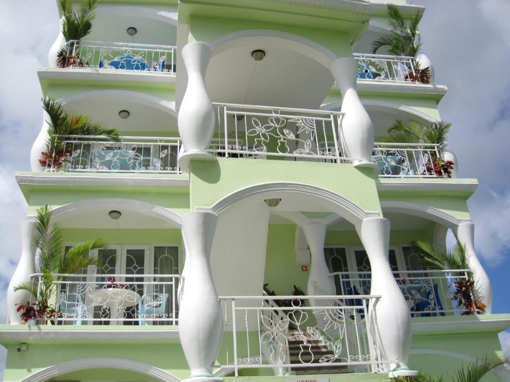 a tall white building with balconies and tables at Villa Kissen in Trou aux Biches