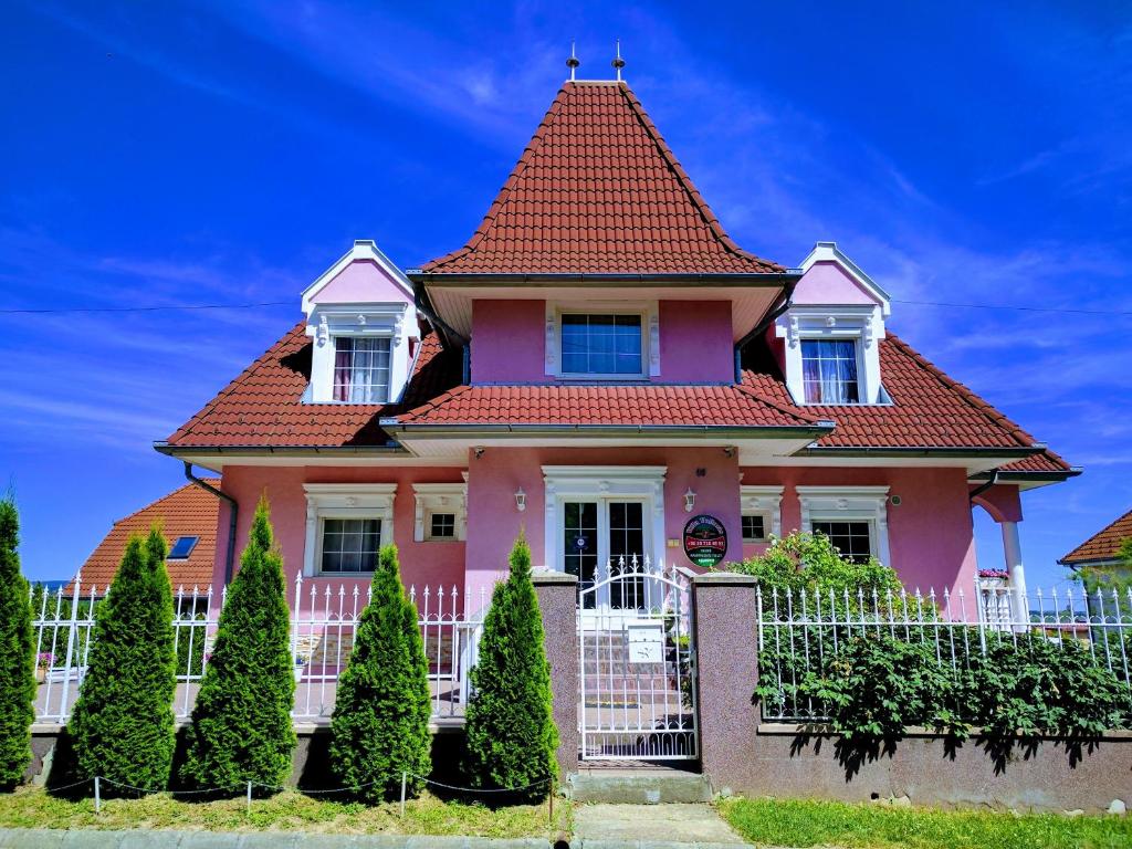 een roze huis met een rood dak bij Valloris Apartments in Hévíz