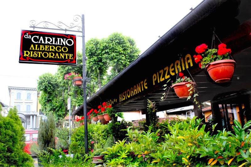 un restaurante con macetas de flores al lado de un edificio en Albergo Ristorante Da Carlino, en Castelnuovo di Garfagnana