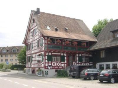 un gran edificio de madera con coches aparcados delante de él en Hotel Restaurant Pizzeria Rotes Haus, en Münsterlingen