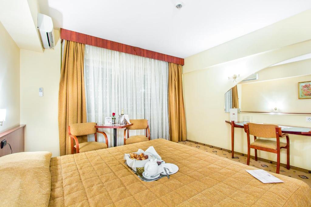a hotel room with a bed with a tray of food on it at Caro Hotel in Bucharest