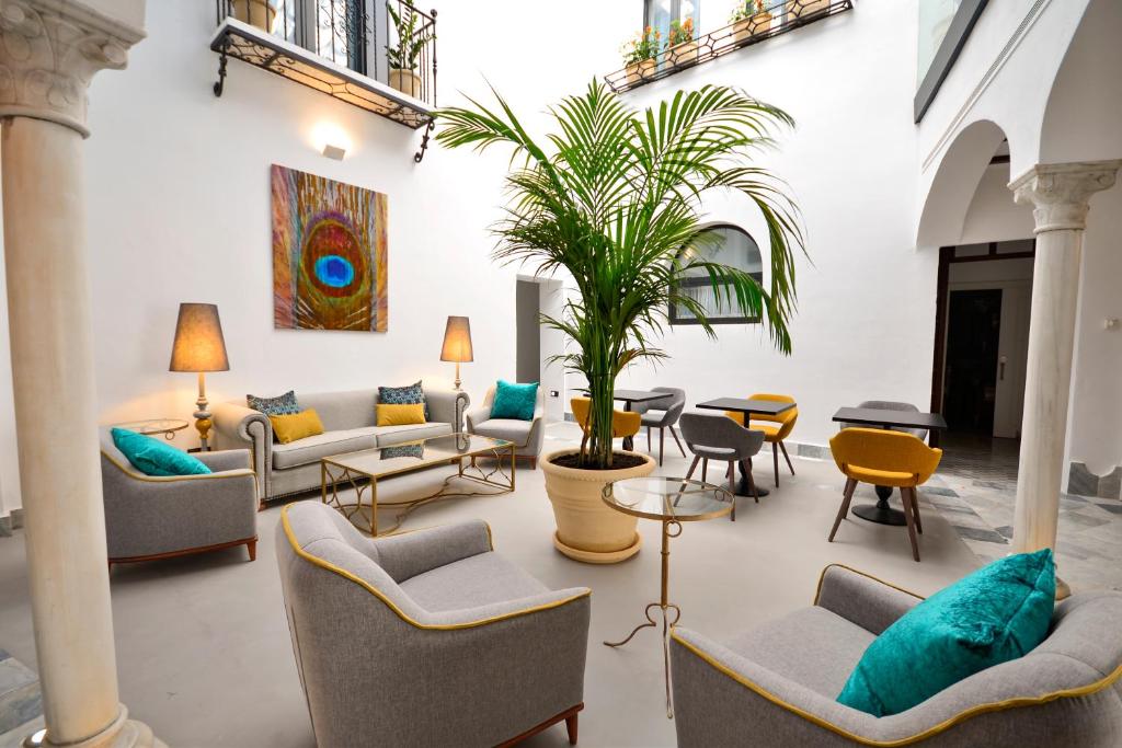 uma sala de estar com sofás e um vaso de plantas em Hotel Legado Alcazar em Sevilha