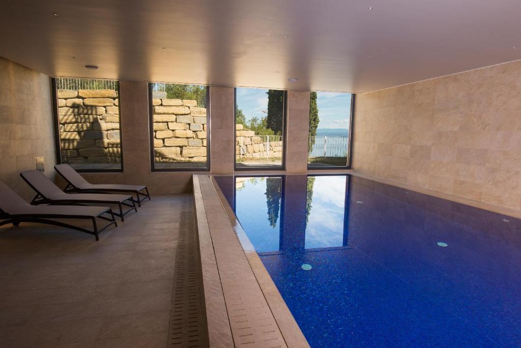 a swimming pool in a building with two chairs at Hotel Cliff Belvedere in Izola
