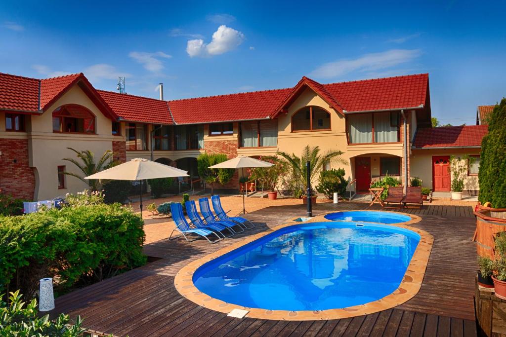 a swimming pool in front of a house at Ópusztaszeri Erdei Wellness Vendégház in Ópusztaszer