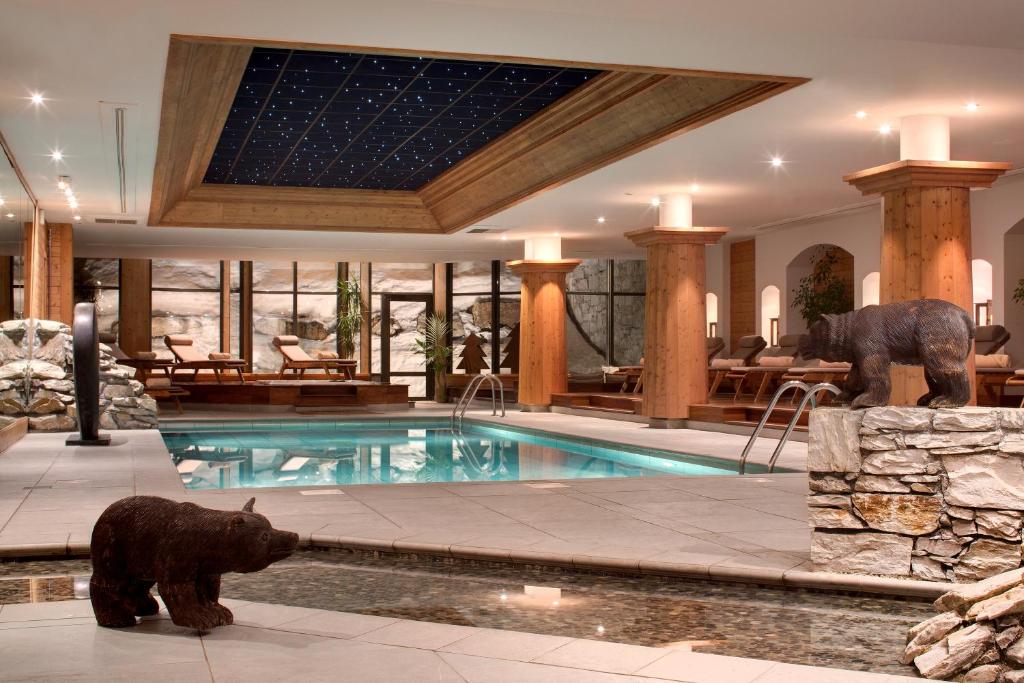 a house with a swimming pool with a bear statue at Hôtel Les Barmes De l'Ours in Val dʼIsère