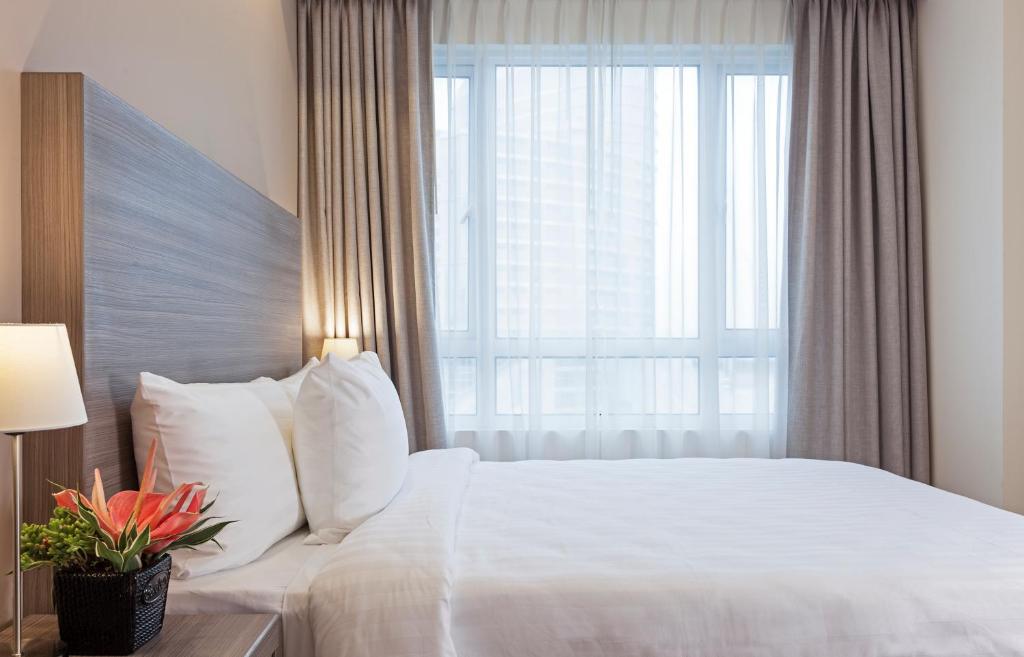 - une chambre avec un lit blanc et une grande fenêtre dans l'établissement One Pacific Place Serviced Residences, à Manille