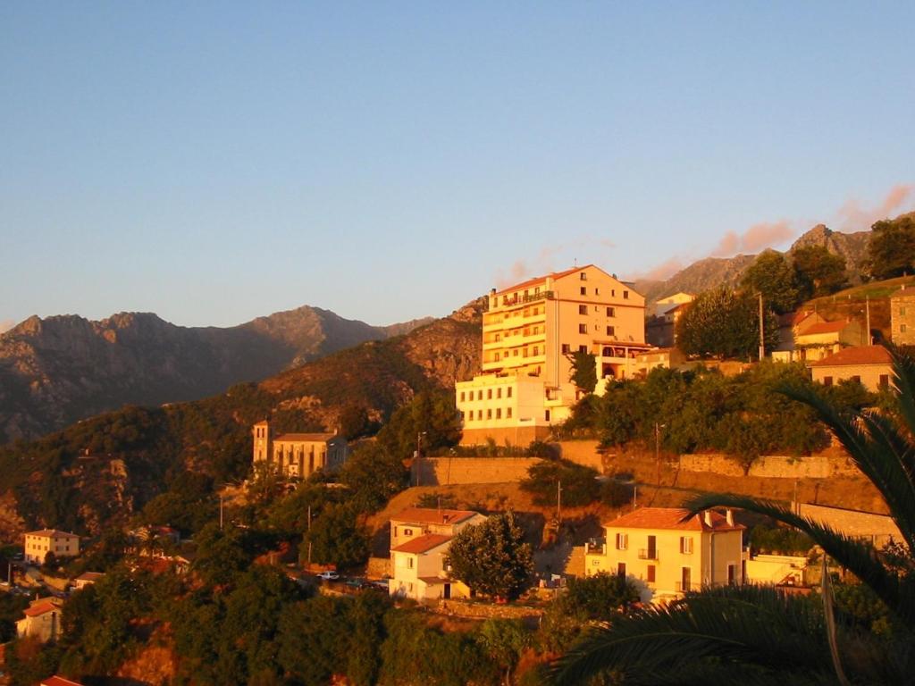 una ciudad en una colina con montañas en el fondo en Hôtel Restaurant Sole e Monte, en Cuttoli-Corticchiato