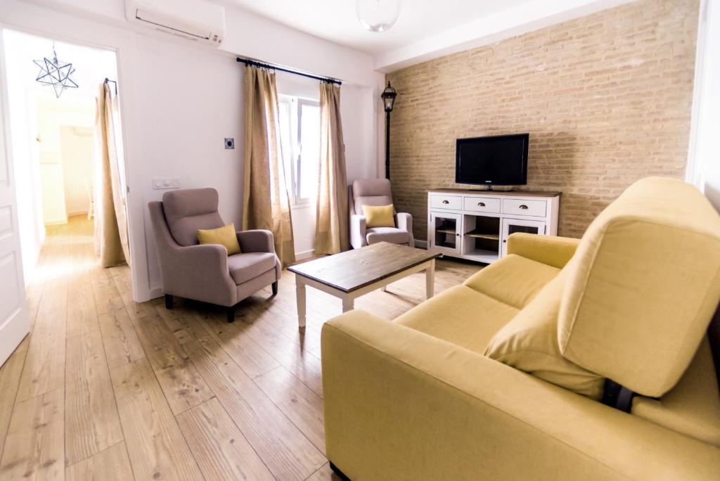 ein Wohnzimmer mit einem Sofa, Stühlen und einem TV in der Unterkunft Apartment in the centre (Judería) in Sevilla