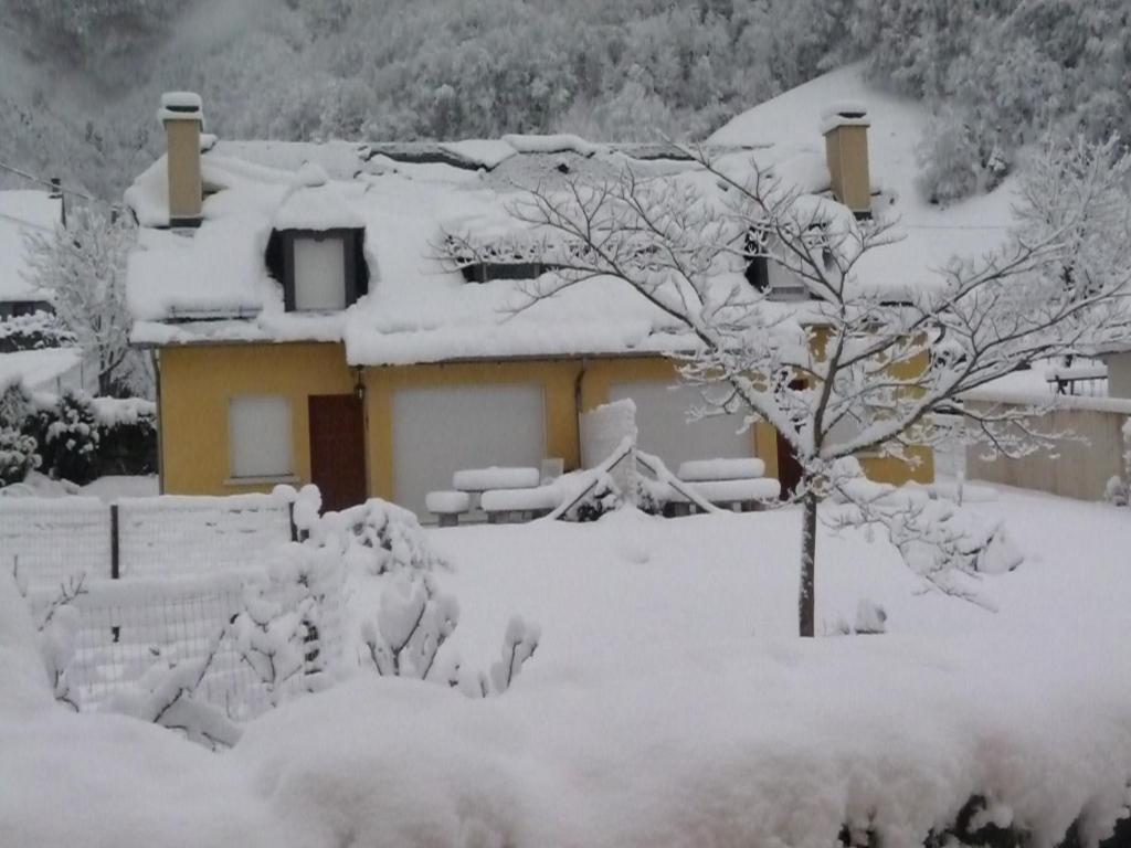 une maison recouverte de neige avec un arbre dans l'établissement Gite La Balaguere, à Cauterets