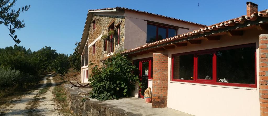 una casa de ladrillo con ventanas rojas en un camino de tierra en Quinta Casal Maio, en Sertã