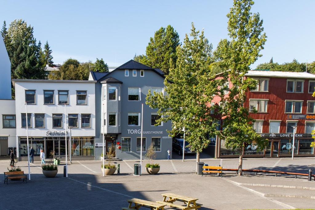 un grupo de edificios en una plaza de la ciudad con bancos en Torg Guest House, en Akureyri