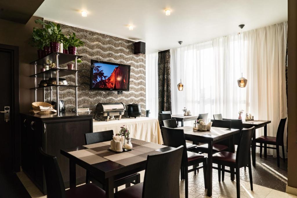 a dining room with tables and chairs and a tv on a wall at Business Hotel Diplomat in Nizhny Novgorod