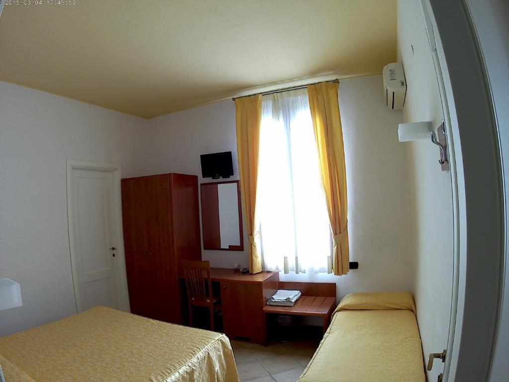 1 dormitorio con 2 camas, escritorio y ventana en Bed And Breakfast Perla Del Sole, en Arenella