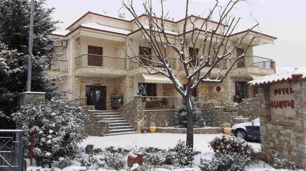 a snow covered house with a tree in front of it at Hotel Philippion in Kato Loutraki
