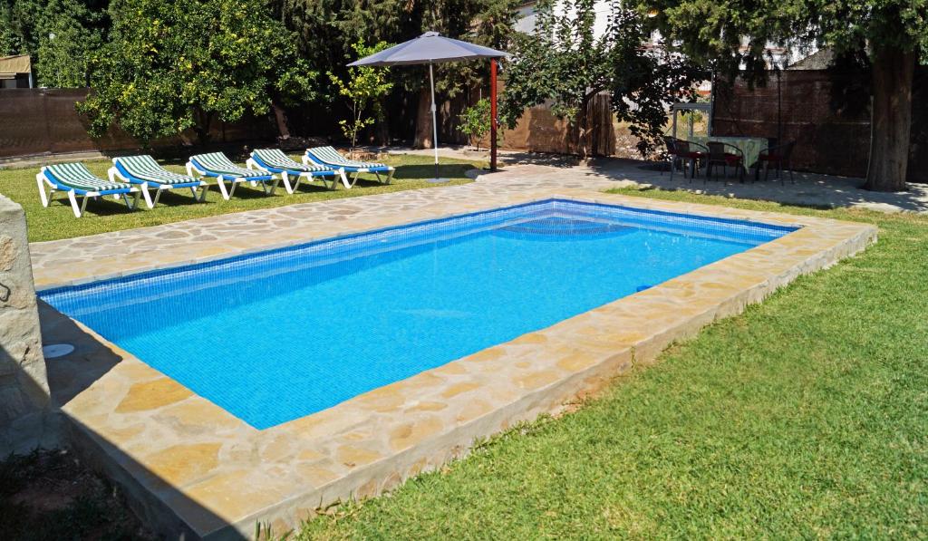 uma piscina na relva com cadeiras e um guarda-sol em Casa Rural Los Cipreses em Benaoján