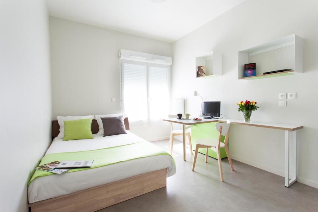 - une chambre blanche avec un lit et un bureau dans l'établissement L'Aéronat by Popinns, à Saint-Cyr-lʼÉcole