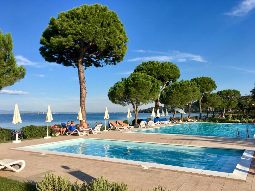 basen z drzewami i ocean w tle w obiekcie Le Corti Del Lago w mieście Padenghe sul Garda