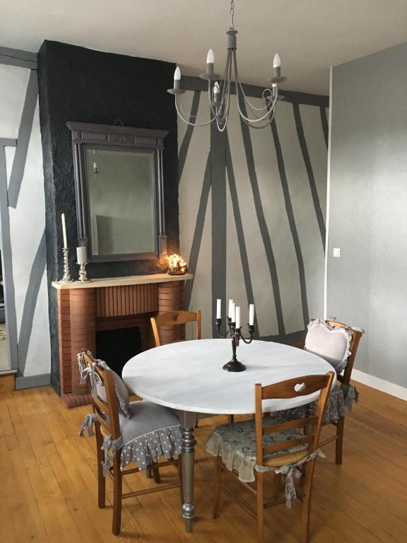 uma sala de jantar com uma mesa e cadeiras e uma lareira em gite du moulin em Aumale