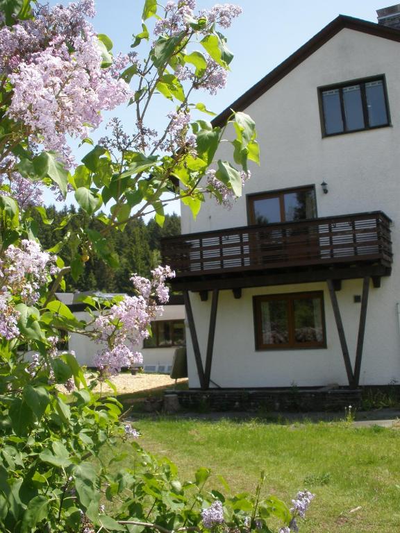 a white house with a balcony and flowering trees at Ferienwohnungen Federleicht in Titisee-Neustadt