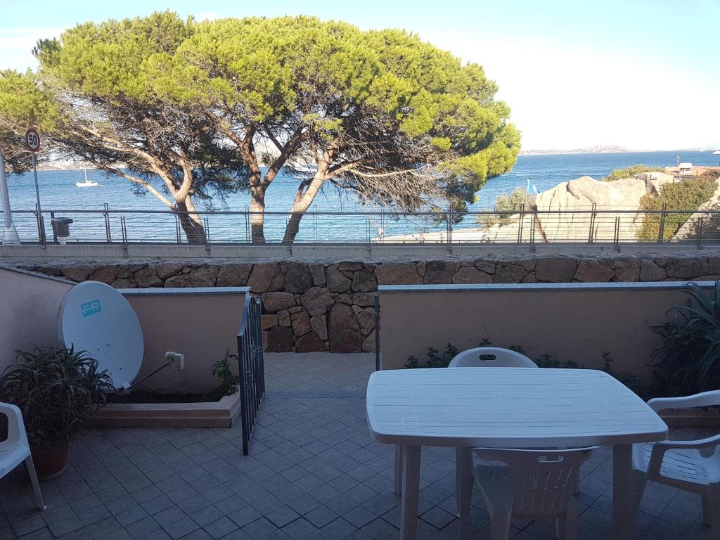 una mesa y sillas en un patio con vistas al océano en Appartamenti Le Gemme, en Palau