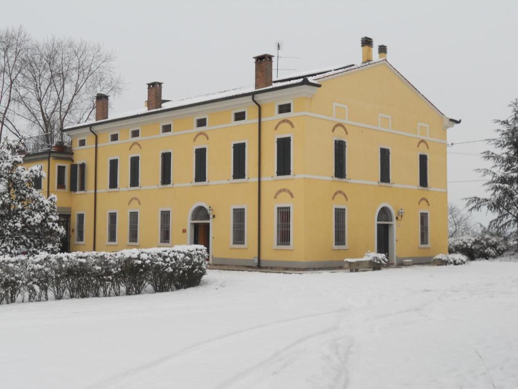 un grand bâtiment jaune avec de la neige au sol dans l'établissement Agriturismo Boaria Bassa, à Castel dʼArio