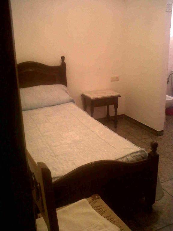 a small bedroom with a bed and a table at Hostal Medina in Olvera