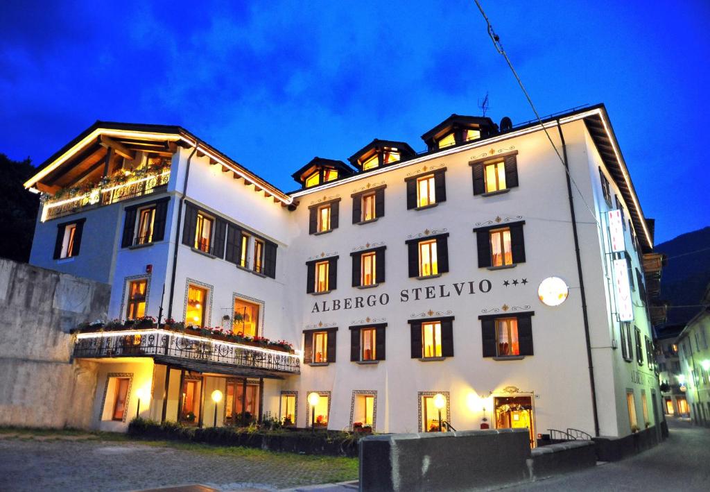 ein großes weißes Gebäude mit Licht an in der Unterkunft Albergo Stelvio in Bormio