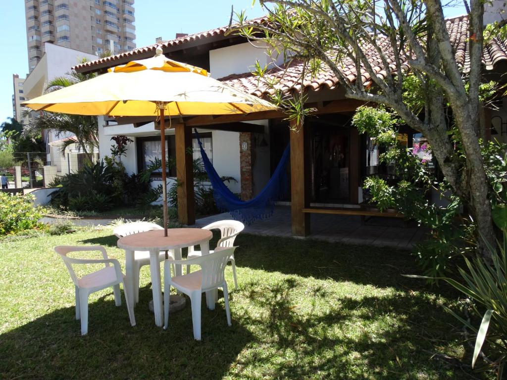 a table and chairs and an umbrella in a yard at Casa Na beira Mar em Torres in Torres