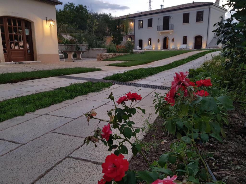 un jardin avec des fleurs rouges et un bâtiment dans l'établissement Il Mulino della Signora Luxury country House, à Frigento