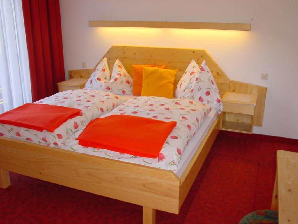 ein Holzbett mit bunten Kissen darauf in der Unterkunft Apartments Wrolich in Latschach ober dem Faakersee
