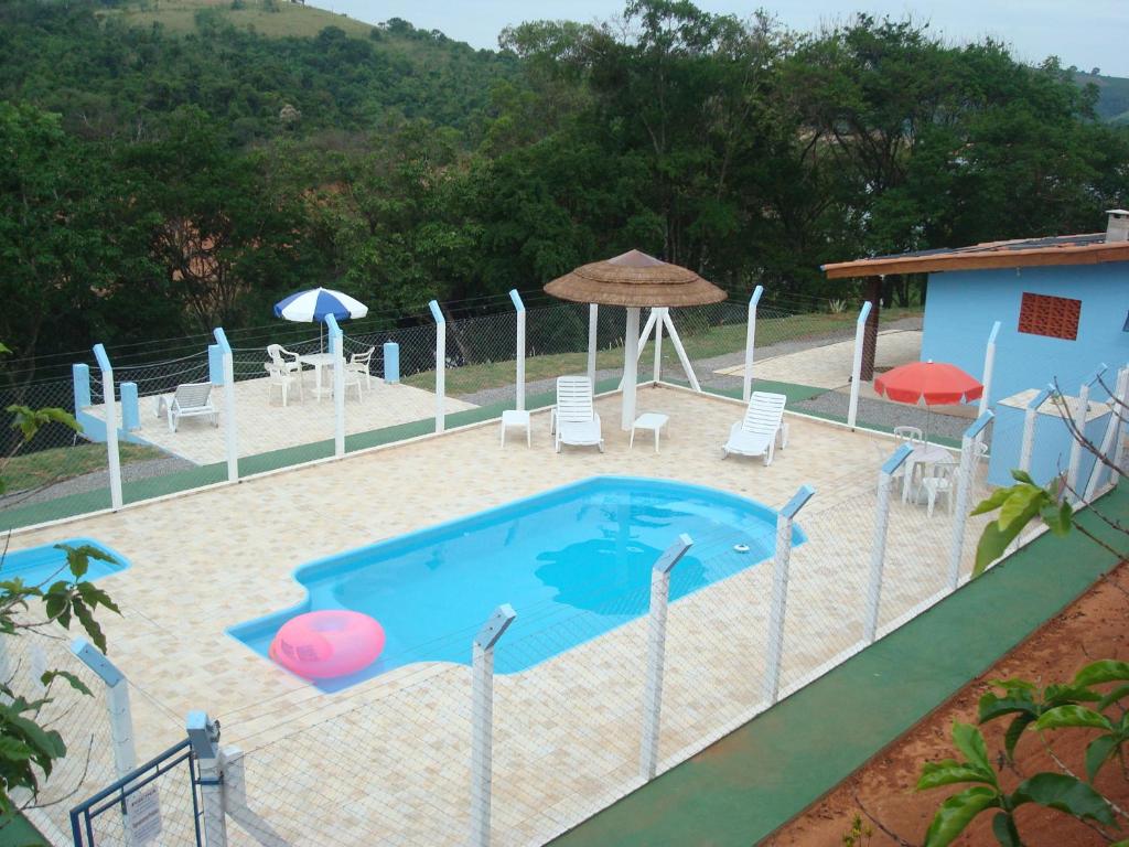 a pool with chairs and umbrellas next to a house at Recanto Bela Vista in Caconde