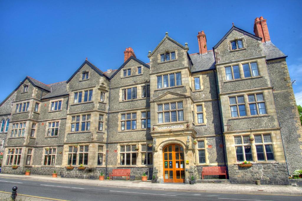 a large brick building with a clock on the side of it at George IV Hotel in Criccieth