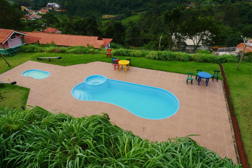 een groot zwembad in een tuin met tafels en stoelen bij Pousada Spa Saúde Melhor in Extrema